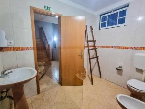 a bathroom with a toilet and a wooden door at Casa Martins by Tear in Aldeia de João Pires +21 photos