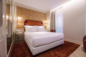a bedroom with a large white bed and a desk at Olympia Lis Baixa Hotel in Lisbon