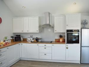 a white kitchen with white cabinets and a refrigerator at The Stables - Uk13196 in Butterwick +18 photos
