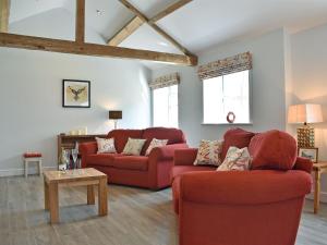 a living room with two red couches and a table at The Stables - Uk13196 in Butterwick