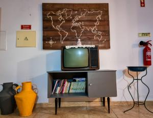 a television sitting on a tv stand with a book shelf at Casa Martins by Tear in Aldeia de João Pires