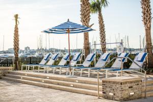 rząd niebiesko-białych krzeseł i parasol w obiekcie The Beach Club at Charleston Harbor Resort and Marina w mieście Charleston