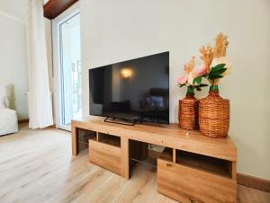 a living room with a television and two vases with flowers at Le repère des amis - 4 pers - proche tram - parking gratuit - babyfoot in Lingolsheim