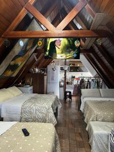 a attic room with four beds and a flat screen tv at Canto Gira Sol - Estúdio Borboleta in Penha