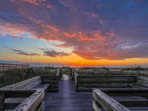 a wooden boardwalk to the beach at sunset at T.L. Sea - KDH MP 6, Oceanfront, Ocean view, Rec Room, Spacious Decks, Private Walk to Beach in Kill Devil Hills