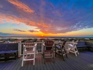 two chairs and a table on a deck with a sunset at T.L. Sea - KDH MP 6, Oceanfront, Ocean view, Rec Room, Spacious Decks, Private Walk to Beach in Kill Devil Hills