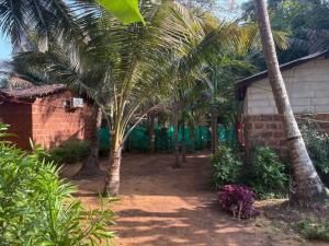 a group of palm trees next to a house at Beach Farm Stay in Gokarna