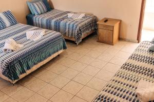 two beds in a room with a tiled floor at Niv's Hotel in Monte Sião
