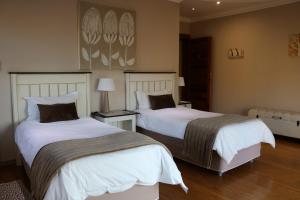 a bedroom with two beds with white sheets at Highland Gate Golf & Trout Estate, House 925 in Dullstroom