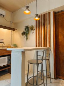 a kitchen with a counter and two stools at Espaços Cardoso, AURORA - luz e leveza in Igrejinha