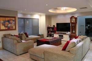a living room with two couches and a flat screen tv at Highland Gate Golf & Trout Estate, House 925 in Dullstroom