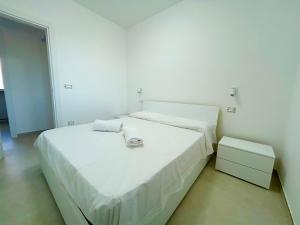 a white bedroom with a large bed and a night stand at Sea Apartment - Torre Pali in Torre Pali
