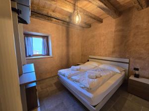 a bedroom with a bed with white sheets and pillows at Corte Cimiotti - Borgo Gortani in Sùtrio