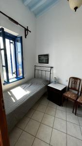 a bedroom with a bed and a chair and a window at Camaraki Capitano House , Chora Serifos in Serifos Chora