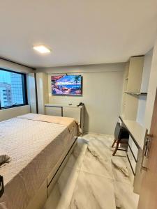 a bedroom with a bed and a desk and a window at Estilo e Praticidade - Seu Flat ao lado do mar in São Luís