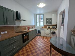 a kitchen with green cabinets and a checkered floor at Le Tintamarre - Chambres et suite familiale à 5 min du Zoo de Beauval in Saint-Aignan