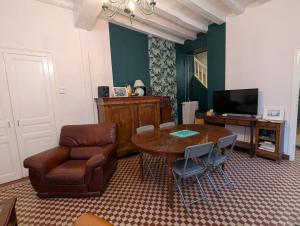 a living room with a table and a chair and a television at Le Tintamarre - Chambres et suite familiale à 5 min du Zoo de Beauval in Saint-Aignan