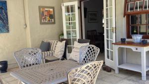 a patio with wicker chairs and a table and a bench at Hillcrest Cottage in Constantia