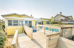 a house with a wooden deck with chairs on it at Gypsea Rose - Southern Shores, Oceanfront, Ocean View, Hot Tub, Pets OK, Flex Stays in Southern Shores