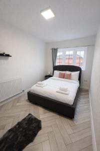 a bedroom with a bed with white sheets and pink pillows at Modern Comfort for Longer Stays in Bury, 2-Bedrooms in Walmersley