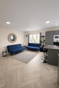 a living room with a blue couch and a kitchen at Modern Comfort for Longer Stays in Bury, 2-Bedrooms in Walmersley