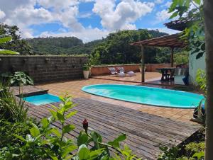 a backyard with a swimming pool and a wooden deck at Chalés na Montanha em Poços de Caldas in Poços de Caldas