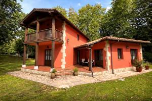 a small orange house with a balcony at Llanes Villa con Piscina y Jardín – Las Ardillas in Cardoso