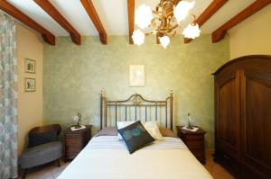 a bedroom with a bed and a chair and a chandelier at Villino AL CASTAGNO in SantʼAlfio