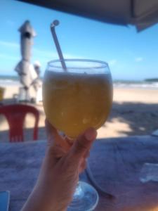 a person holding up a glass of orange juice at Pousada Santa Adélia - Boipeba BA in Ilha de Boipeba