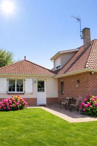 a brick house with a table and chairs in a yard at Chambre d'Hotes Les Hortensias in Rang-du-Fliers