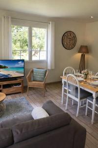 a living room with a couch and a tv and a table at Chambre d'Hotes Les Hortensias in Rang-du-Fliers