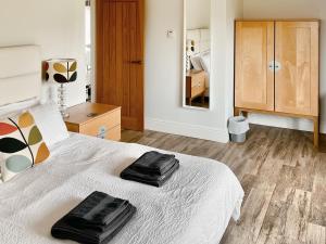 a bedroom with a bed with two black towels on it at Lovells Barn in Welland