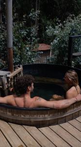 a man and a woman sitting in a hot tub at Surf Lodge Punta de Lobos in Pichilemu