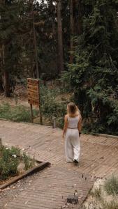 a woman walking down a brick walkway in a forest at Surf Lodge Punta de Lobos in Pichilemu