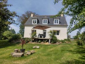 a white house with an umbrella in the yard at Gite des Noës in Lamballe Armor