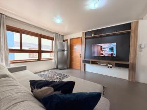 a living room with a couch and a tv at Apartamento Coração de Gramado in Gramado