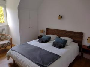 a bedroom with a large white bed with blue pillows at Gite des Noës in Lamballe Armor