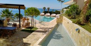 a swimming pool with a table and chairs and the ocean at Your Home Montenegro in Dobra Voda