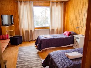 a bedroom with two beds and a tv and a window at Kätkävaara Wilderness Lodge in Muurola