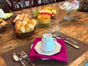a table with a plate of bread and a cup of coffee at Casa Garten by Concavus in Campos do Jordão