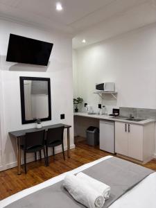 a bedroom with a table and a kitchen with a mirror at Cradock Guest House & Self Catering in Cradock