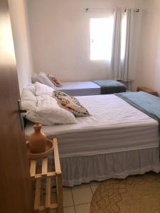two twin beds in a room with a window at Barrah flat in Barra de São Miguel