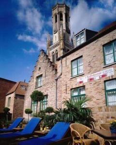 a building with blue lounge chairs and a clock tower at Koffieboontje Budget in Bruges