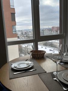 a table with plates and wine glasses and a window at Gold in Chişinău