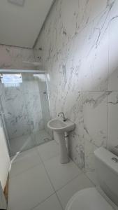 a white bathroom with a sink and a shower at Cantinho dos Pássaros Centro Penedo RJ in Penedo