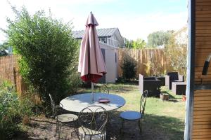 a table with an umbrella and chairs in a yard at Location cocooning à Audenge in Audenge