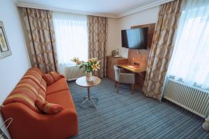 a hotel room with a couch and a desk and a television at Hotel Wagner in Obertauern