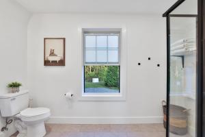 a white bathroom with a toilet and a window at Old Rag Mountain Getaway - WiFi, Smart TV, Fire Pit, Patio, & Full Kitchen in Etlan +16 photos