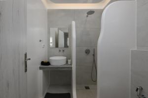 a white bathroom with a sink and a mirror at Anemomylos in Kastraki +18 photos