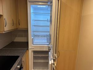 an empty refrigerator with its door open in a kitchen at Ganmos Place in Bracknell